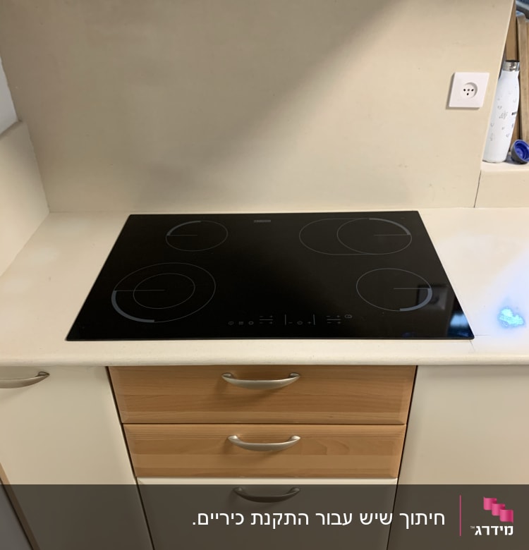 משטח שיש לבן עם כיריים שחורות במטבח מודרני